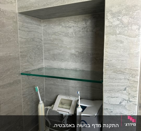 מדף זכוכית עם מברשות שיניים חשמליות ומכשיר